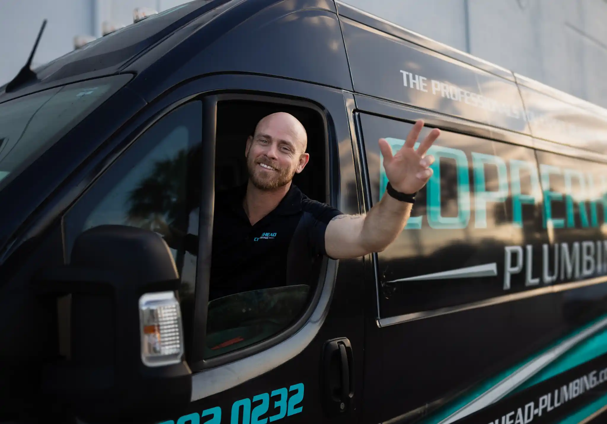 Friendly plumber from Copperhead Plumbing waving from company service van